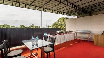 An outdoor patio with a table set for dining, chairs, a grill, and a water dispenser.