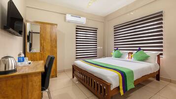 A hotel room with a bed, a desk, a chair, a television, and a window with blinds.