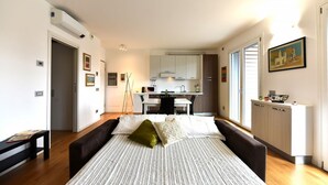 A modern bedroom with a bed, bedside tables, and a view into the kitchen. - GuestHost - Casa Kikka: luminoso bilo con balcone (Cernusco sul Naviglio)