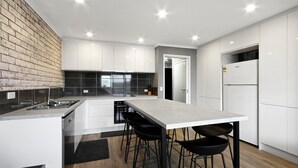 Une cuisine moderne avec des meubles blancs, un plan de travail noir et un îlot central doté de tabourets de bar.