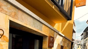 Een hotelgevel van natuursteen, een bord met de naam van het hotel, en een kinderafdekkingsstraat op de achtergrond.
