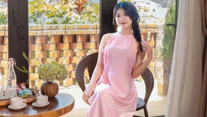 A room with a large window, a wicker chair, a small round table with a vase and a bottle, and a view of the outdoors. - Hoi An Golden Bamboo Villa & Spa (Da Nang)