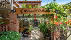 A sign for Golden Bamboo, a villa and spa, with a brick entrance and potted plants. - Hoi An Golden Bamboo Villa & Spa (Da Nang)