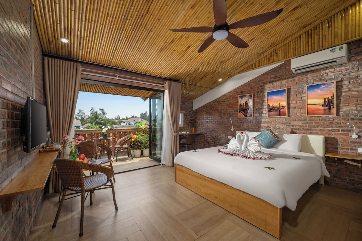 A modern hotel room with a large bed, a desk, and a balcony with a view.