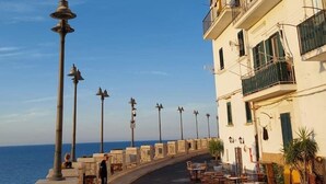 Une promenade en bord de mer bordée de bâtiments, avec des terrasses et des lampadaires.