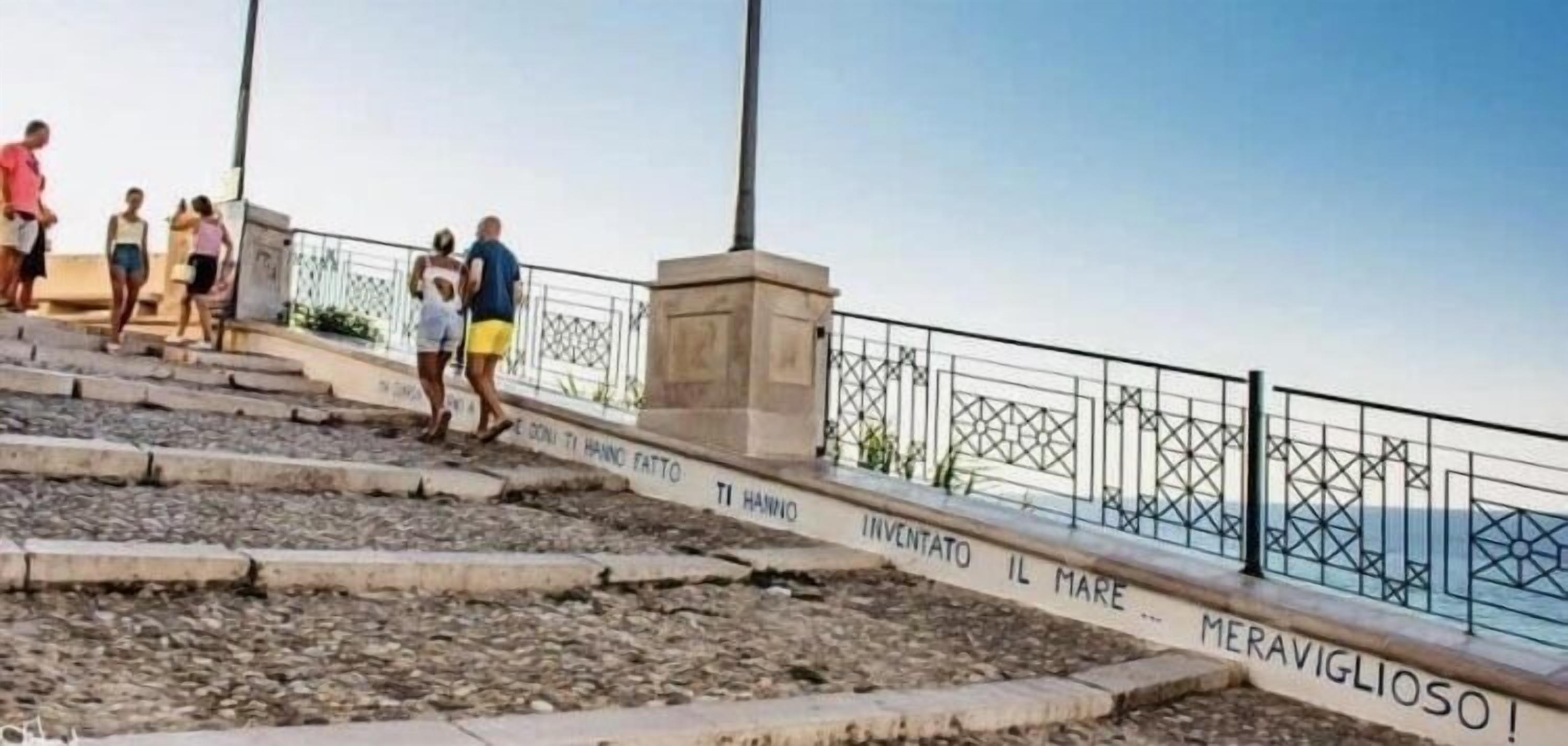 Une série de marches en pierre menant à une balustrade ornée d’inscriptions.