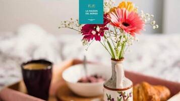 Bandeja de café da manhã com um vaso de flores, um croissant e uma xícara de café.