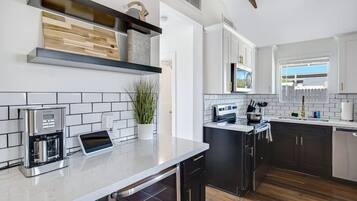 A modern kitchen with a coffee machine, a built-in oven, and a window with a view.