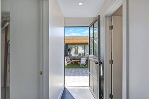 Un pasillo que lleva a un patio con mobiliario exterior y una parrilla.