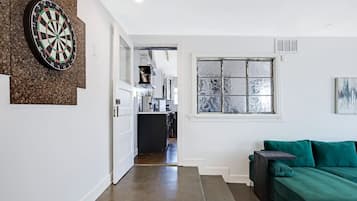 A hallway with a dartboard, a green sofa, and a window with frosted glass.
