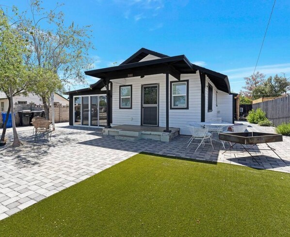 A modern house with a covered patio, a fire pit, and a well-maintained lawn.