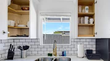 A kitchen with a double sink, wooden shelves, and a window with a view.