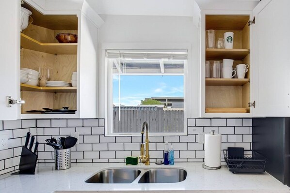 Una cocina con un lavamanos doble, estanterías de madera y una ventana con vistas.