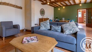 A cozy living room with a blue sofa, a wooden coffee table, and a dining area with a wooden table and chairs. - Spacious Retreat: 5BR, Games Room, Forest Edge, and Large Garden Close to Château and Zoo (Baugé en Anjou)