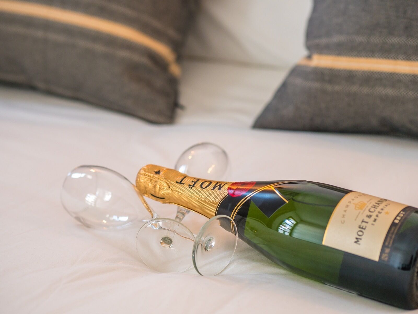 A bottle of Moët & Chandon champagne on a bed with pillows.