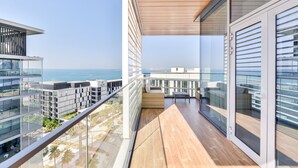 A balcony with a wooden floor, glass railings, and a view of the ocean. - Luxury 2BR plus maids room in Bluewaters (Dubai)