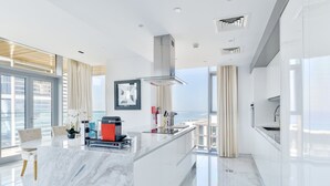 A modern kitchen with a marble island, stainless steel appliances, and large windows offering a view. - Luxury 2BR plus maids room in Bluewaters (Dubai)