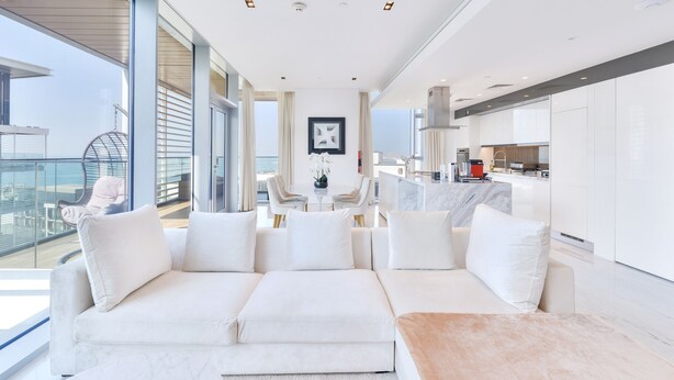 A modern living room with a white sofa, a coffee table, and a balcony with a glass railing. - Luxury 2BR plus maids room in Bluewaters (Dubai)