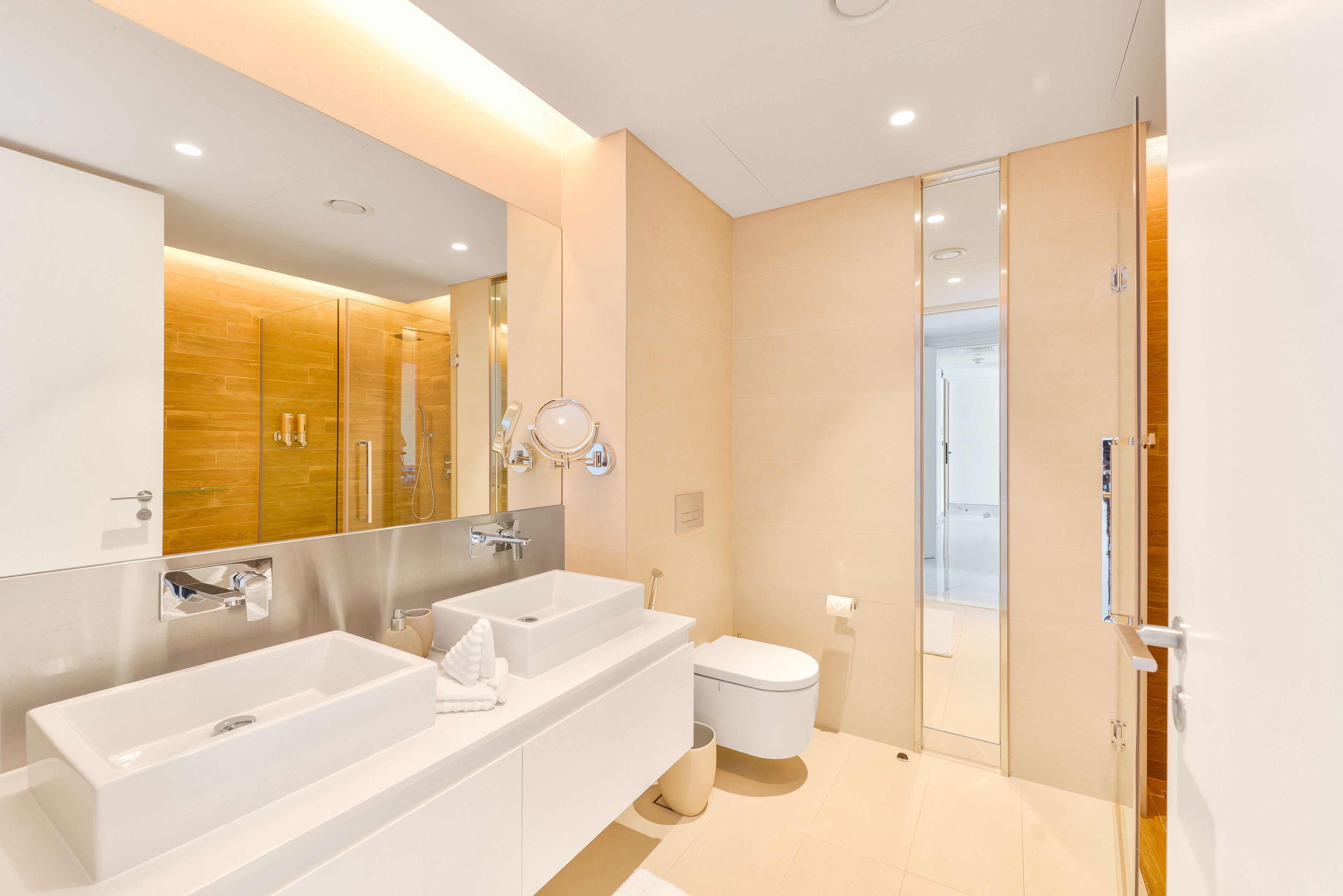 A modern bathroom with two sinks, a toilet, and a glass shower enclosure.