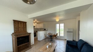 A living room with a fireplace, a sofa, a coffee table, and a dining area with chairs and a table.