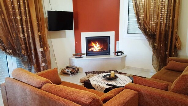 A living room with a fireplace, two sofas, a coffee table, and curtains. - Sweet Little Home Trikala (Pyli)