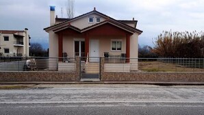 A two-story house with a red roof and beige walls, a front door, and a small porch area. - Sweet Little Home Trikala (Pyli)