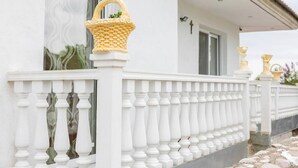 Un balcon blanc, doté de balustrades et orné d’un panier en osier sur le garde-corps.