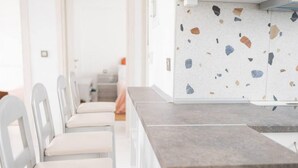 Une cuisine moderne avec des chaises blanches et un revêtement mural en terrazzo.