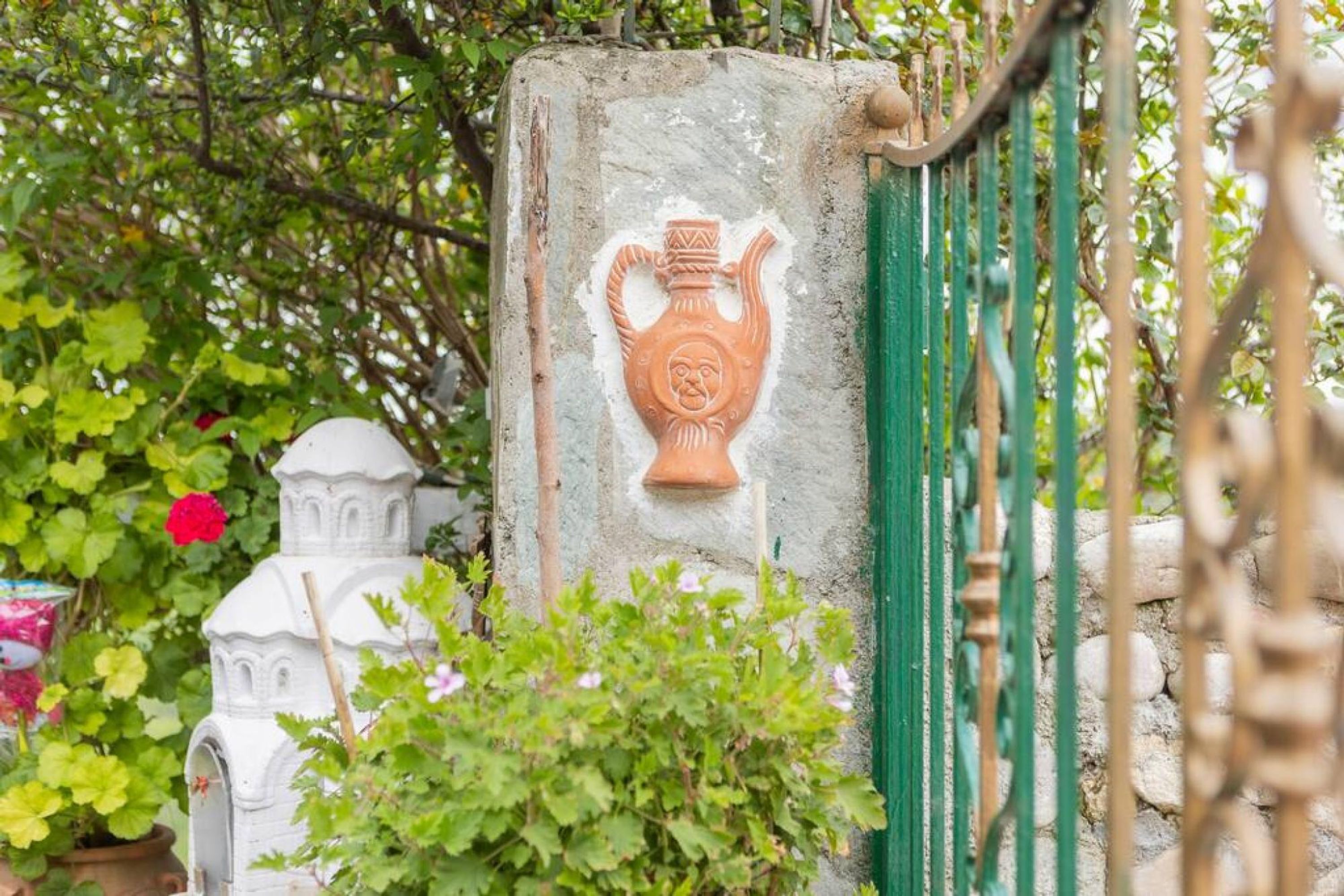 A stone structure with a carved pot and a white building with a dome.