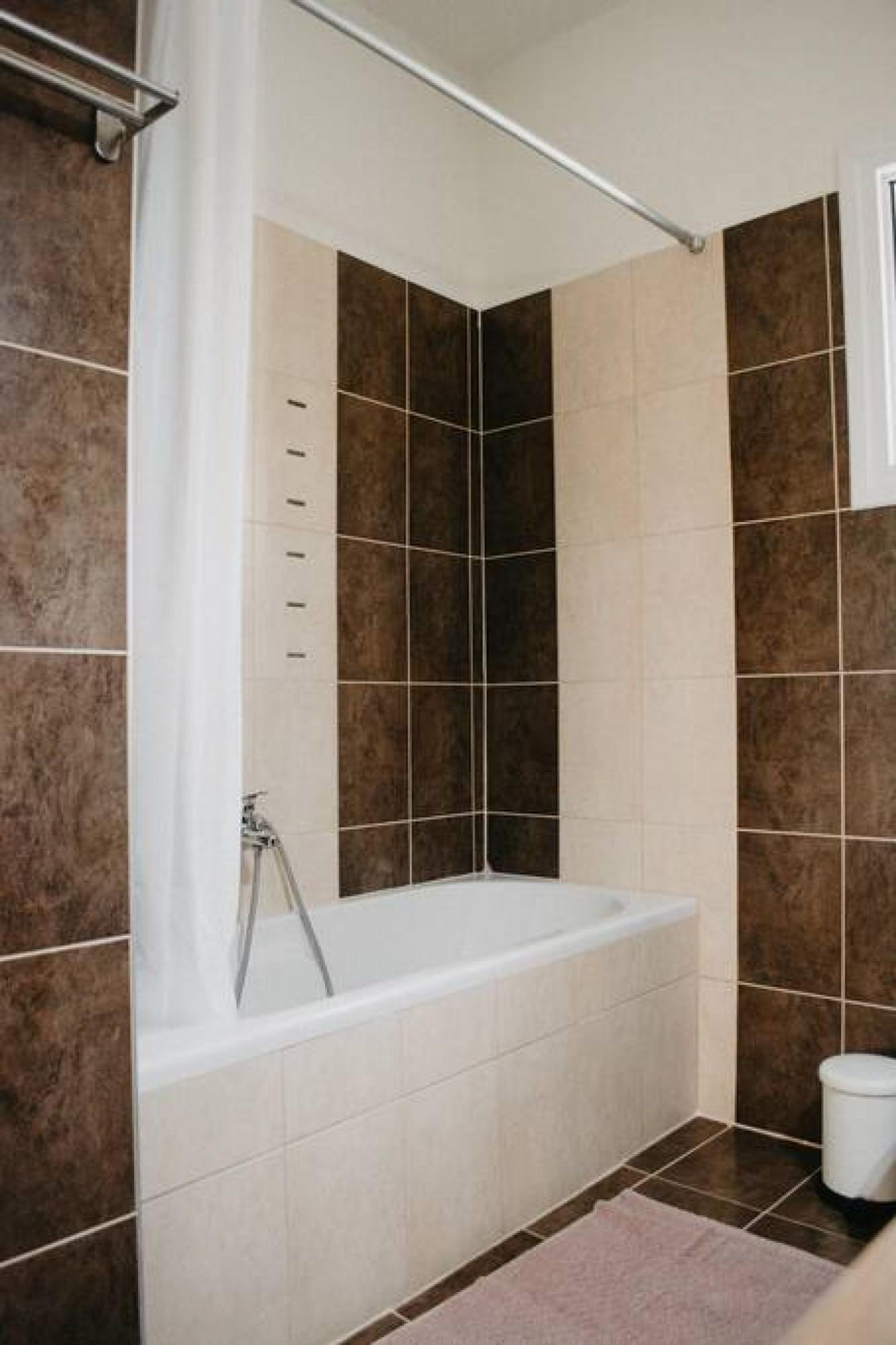 A bathroom with a bathtub, tiled walls, and a shower curtain rod.