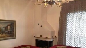 A living room with two red sofas, a glass coffee table, a fireplace, and a chandelier. - Alex s Apartment in Trikala (Trikala)