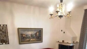 A living room with a red sofa set, a wooden coffee table, a fireplace, and a chandelier. - Alex s Apartment in Trikala (Trikala)