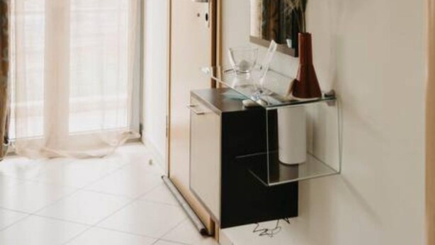 A modern bathroom with a glass shower enclosure, a mirror, and a small shelf with toiletries. - Dimsim Home- House With Name (Trikala)