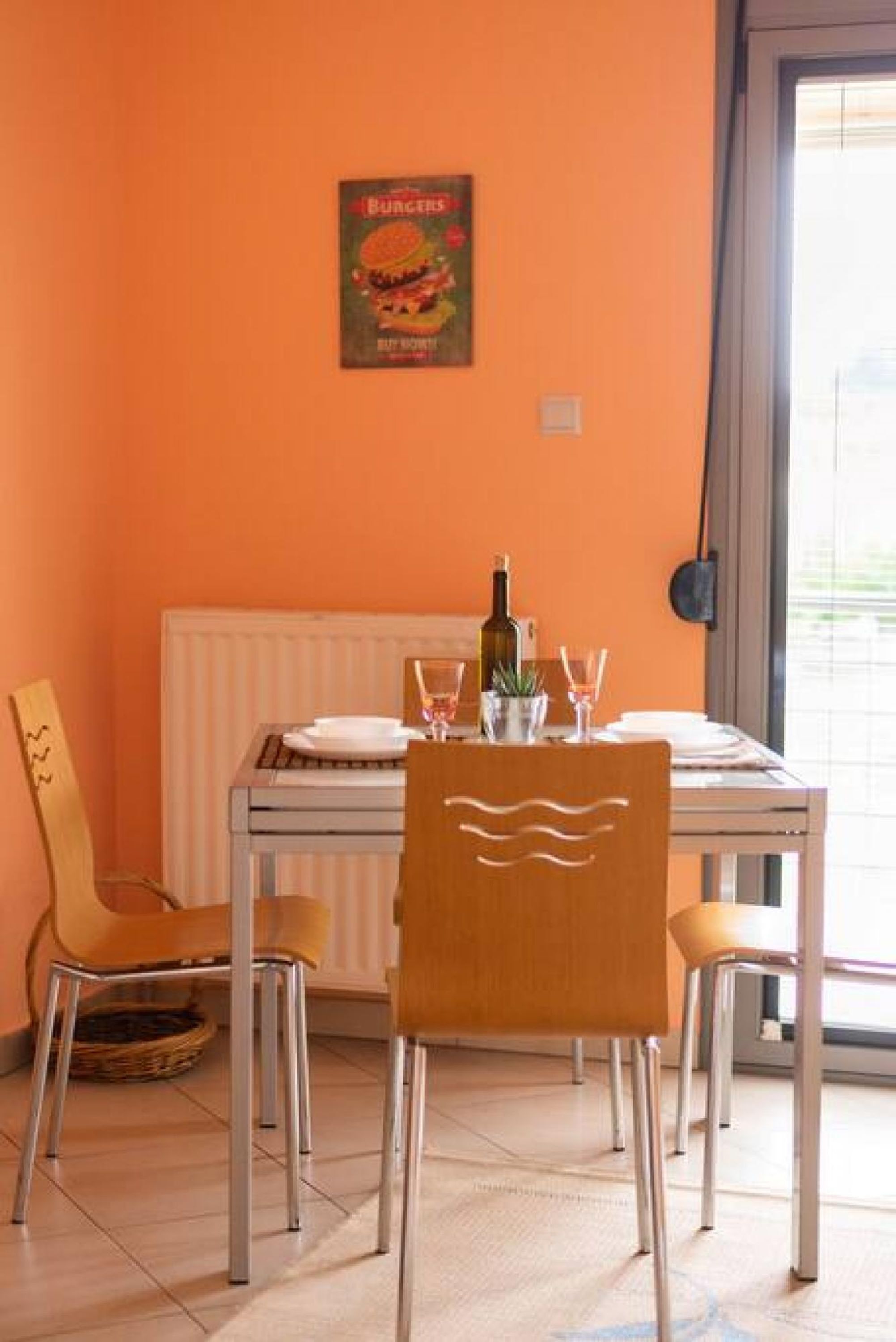 A dining area with a table set for two, a bottle of wine, and a menu on the wall.