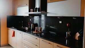 A modern kitchen with black countertops, beige cabinets, and a stainless steel range hood. - Dimsim Home- House With Name (Trikala)