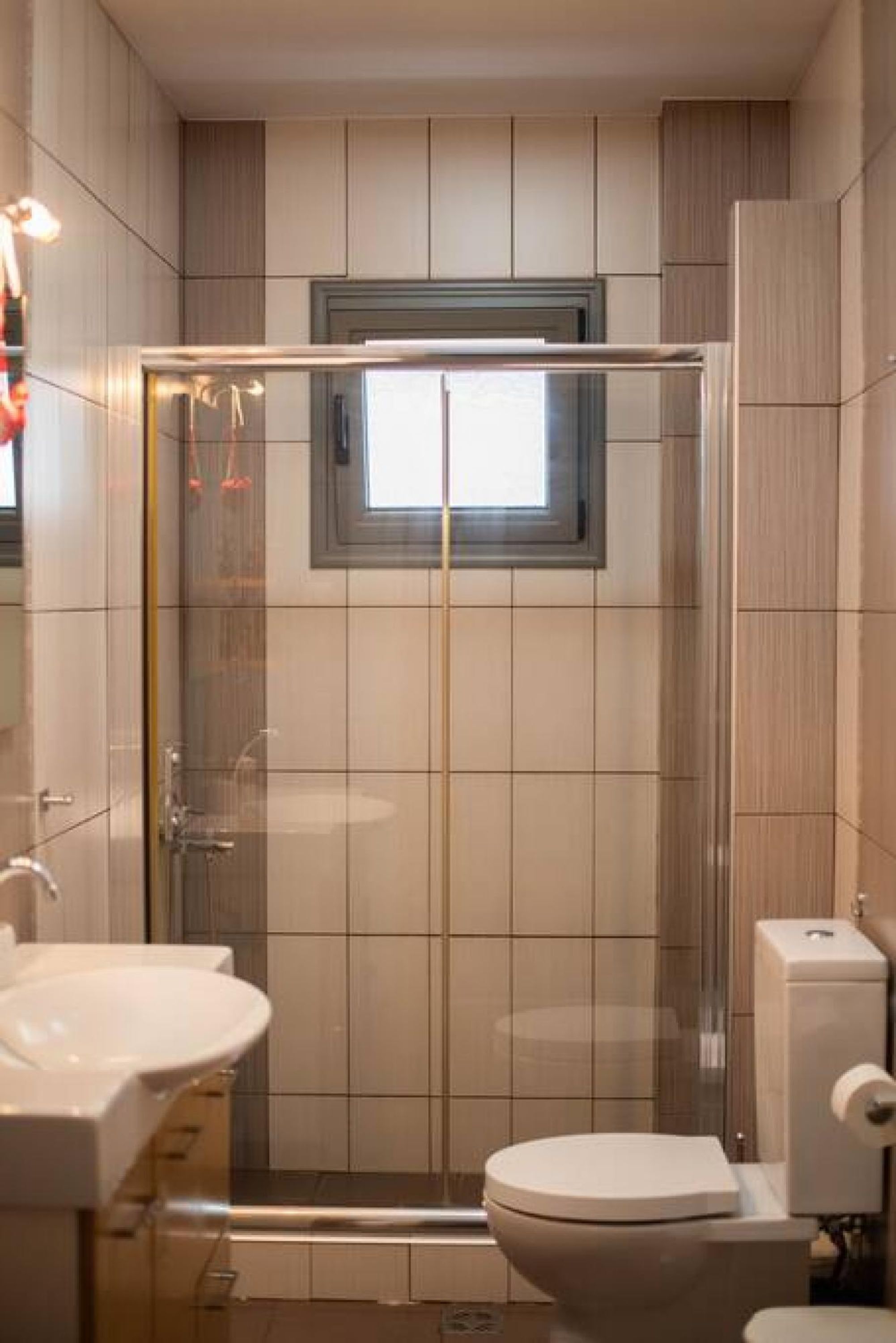 A modern bathroom with a glass-enclosed shower, a toilet, and a sink.