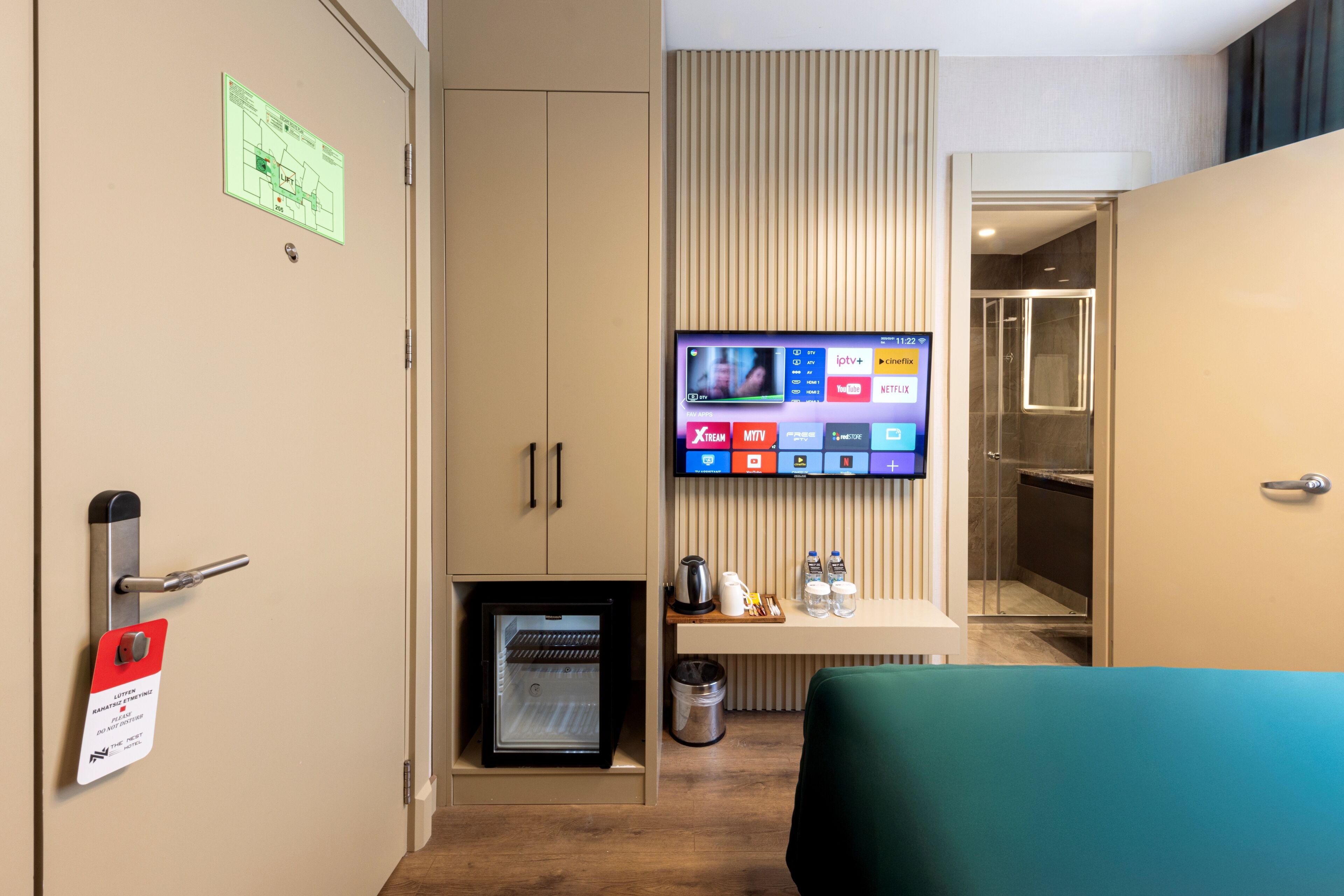 A hotel room with a minibar, a television displaying streaming services, and a small refrigerator.