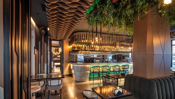 A modern bar area with a curved ceiling, green plants, and a bar counter with seating. - The Nest Hotel (Istanbul)
