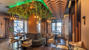 A restaurant interior with a green hanging plant, cushioned seating, and a modern ceiling design. - The Nest Hotel (Istanbul)