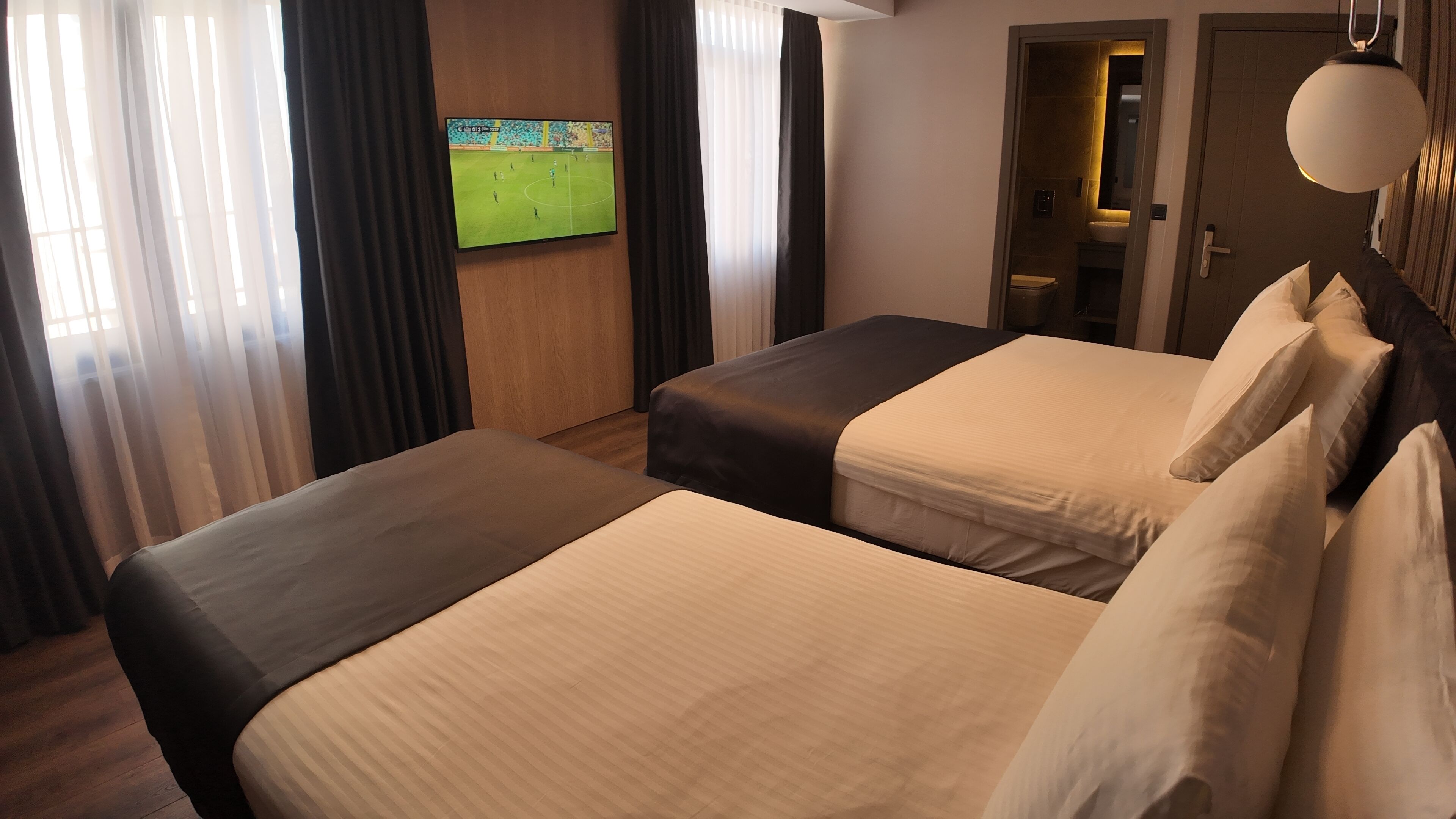 Une chambre d’hôtel avec deux lits, un téléviseur fixé au mur et une porte donnant sur une salle de bain.