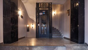 A modern interior with a marble staircase, a black elevator, and wall sconces. - The Nest Hotel (Istanbul)