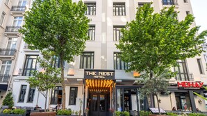 A hotel with a classic facade, a prominent entrance with illuminated signage, and a cafe to the right. - The Nest Hotel (Istanbul)