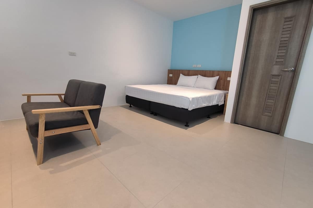 Una habitación con cama, una silla y una puerta.