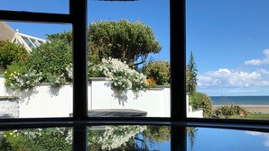 A view through a window with a white wall and greenery, reflecting on a shiny surface. - Thatcher's Rest Cottage
Winner 'Best beach holiday rental in Europe'. (Bettystown)