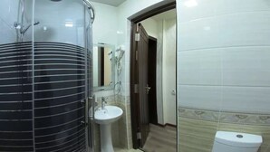 Un baño con un calentador de agua cilíndrico grande, un lavabo y un inodoro.