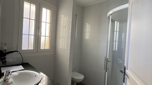 Kylpyhuone, jossa on pesuallas, wc ja lasinen suihkuseinä.
