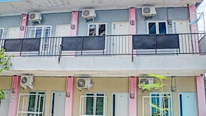 A multi-story building with air conditioning units, shutters, and a balcony with a metal railing. - OYO Life 3248 Vision Residence Karawang (Karawang)
