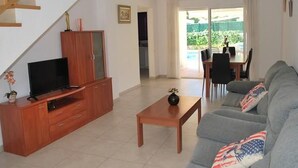 Una sala moderna con un mueble de madera para entretenimiento, un sofá gris con almohadas con la bandera estadounidense, una mesa de centro y una escalera que conduce a otro nivel.