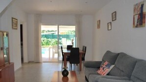 Una sala de estar con un sofá gris, una mesa de centro de madera y una zona de comedor con una mesa y sillas.