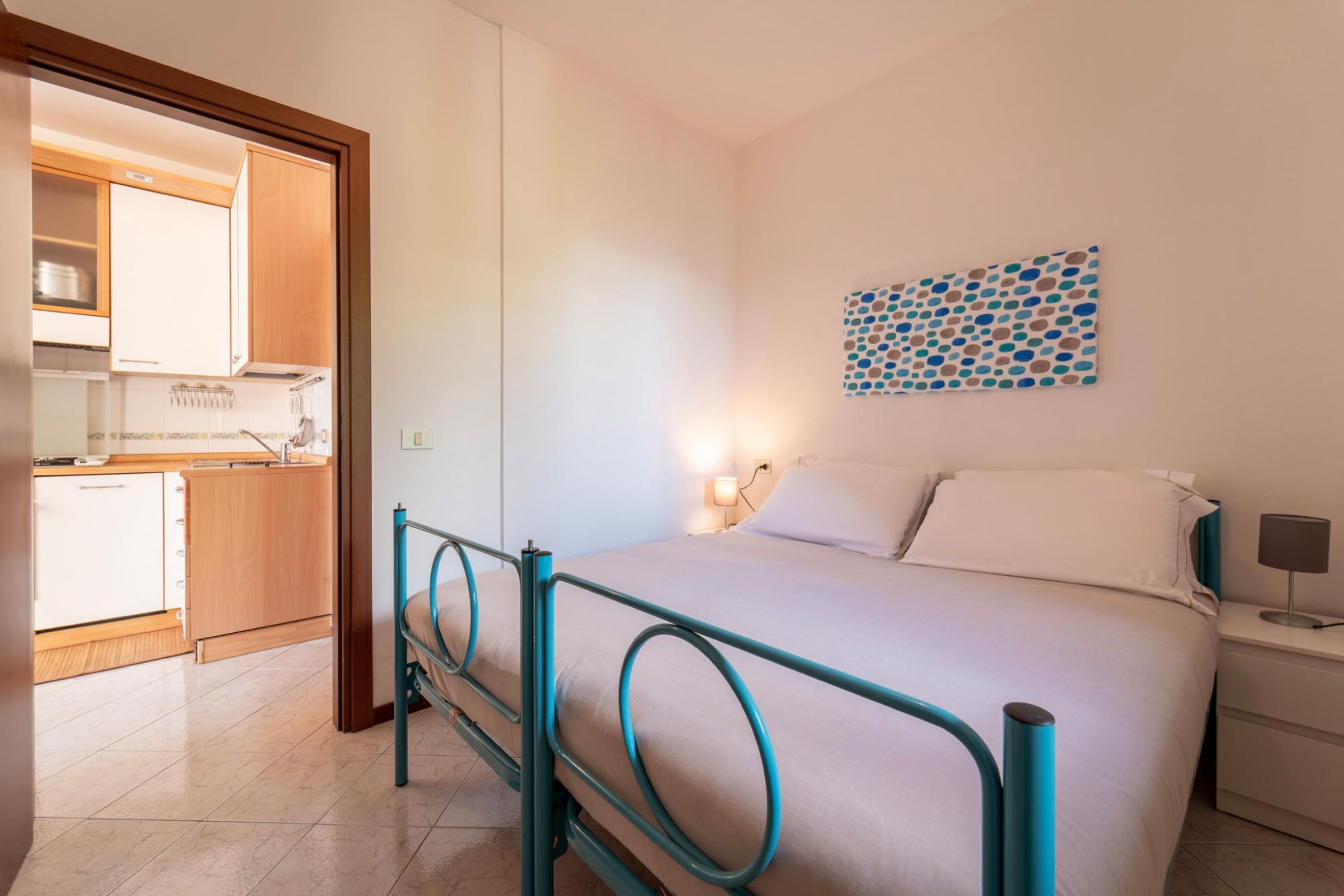 Un dormitorio con cama, mesita de noche y lámpara fijada a la pared.